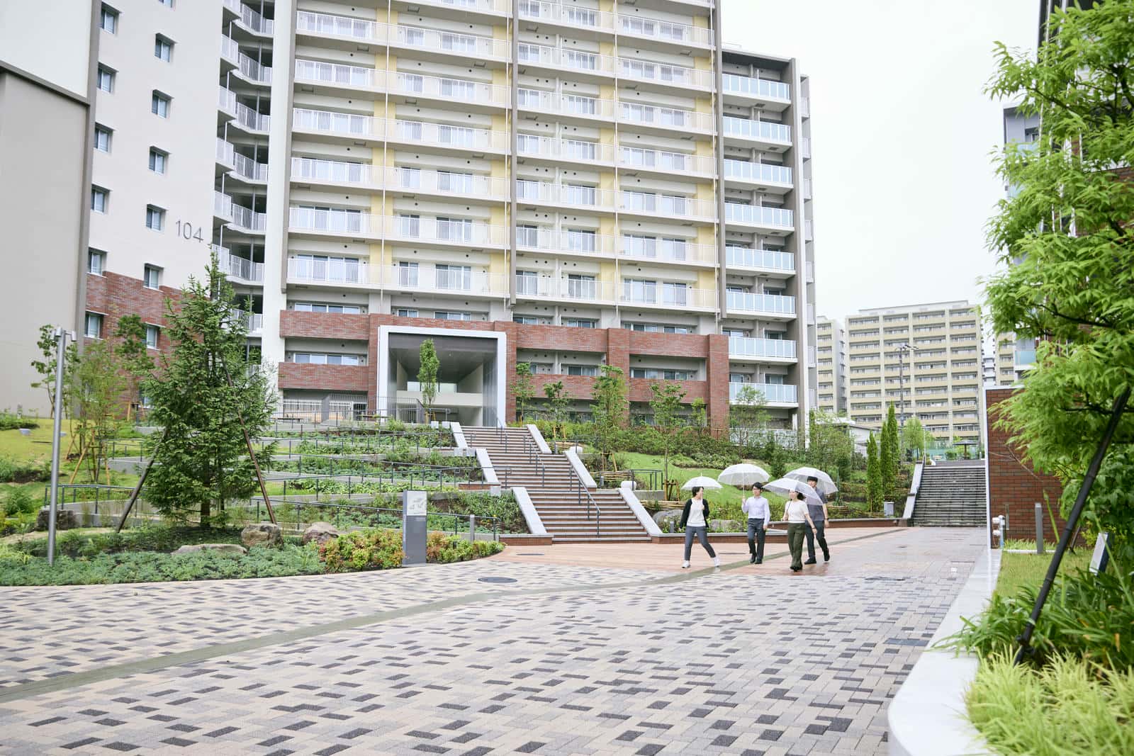 新千里東町団地104号棟前の道を歩く3人