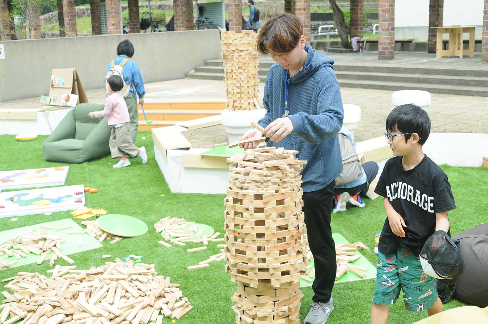 タワーづくりをする学生と子ども