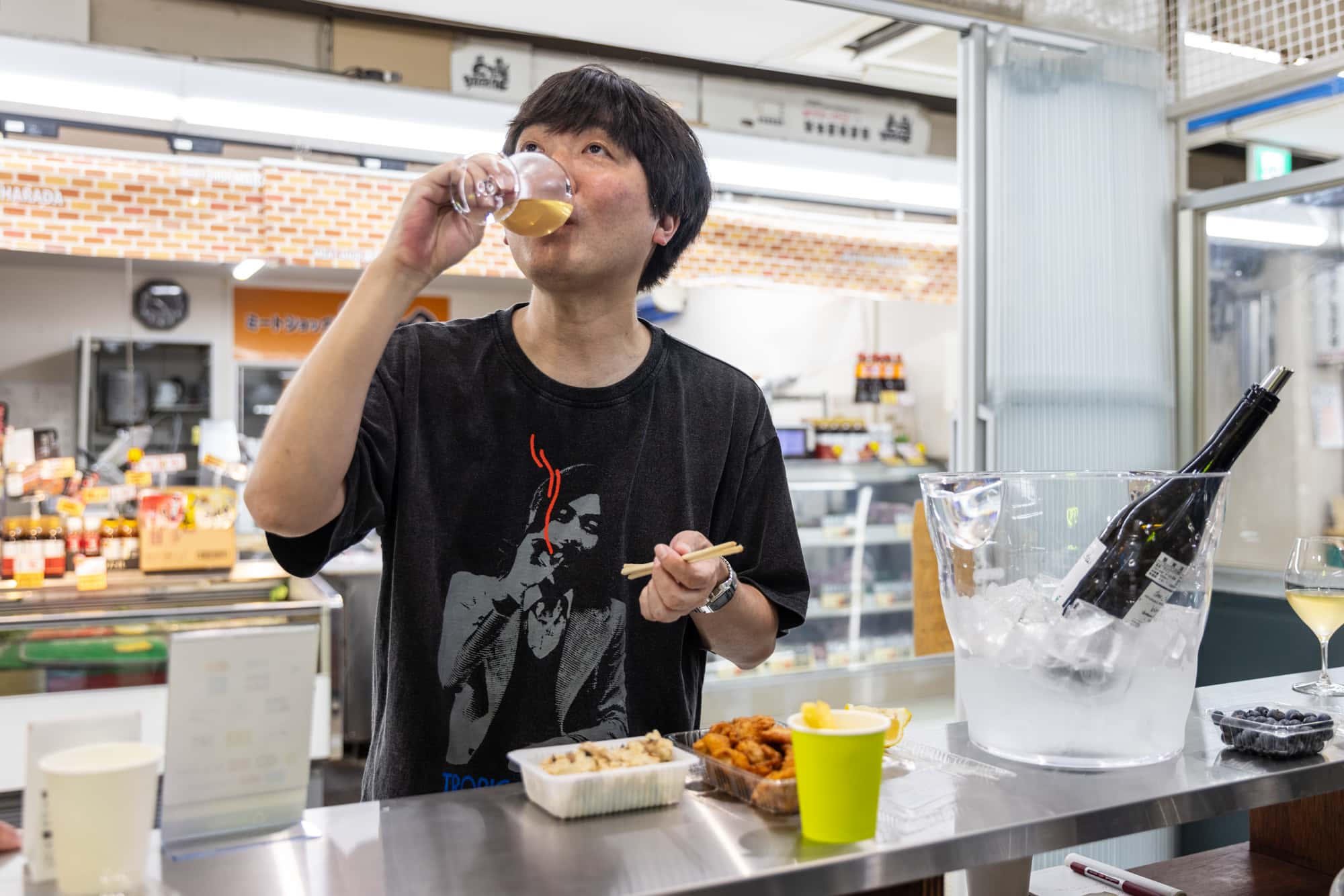 ワインショップで市場飲みを楽しむスズキナオさん