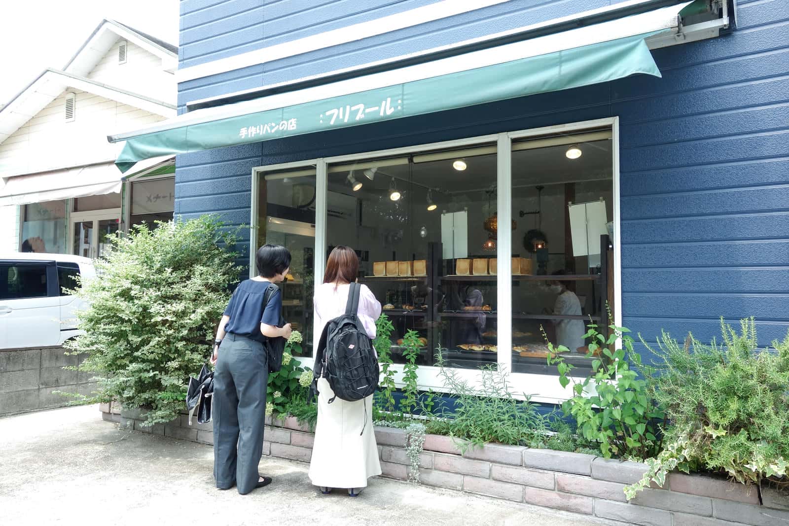 パン屋さんの外から中をのぞきこむ岸本さんと井之上さん