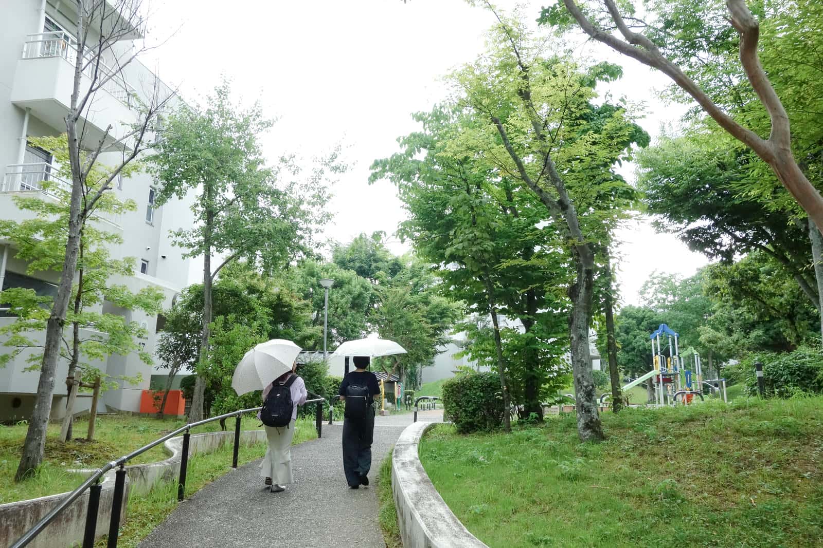 平城右京団地の遊歩道を傘をさしながら歩く2人